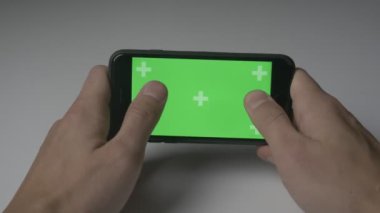 Yakın kadar adam Plaing oyunları ile Smartphone yeşil ekran Chroma Key beyaz Resepsiyon arka plan üzerinde