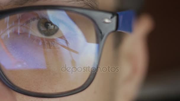 Крупним планом відображення в окулярах чоловіка, який дивиться фільм. Подвійне викриття хлопця, який дивиться відео. Макро — стокове відео