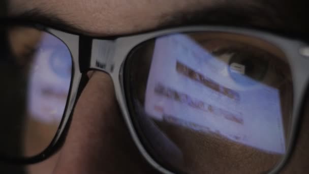 Gros plan de Réflexion sur les lunettes et les yeux des jeunes hommes naviguant sur les sites Internet — Video