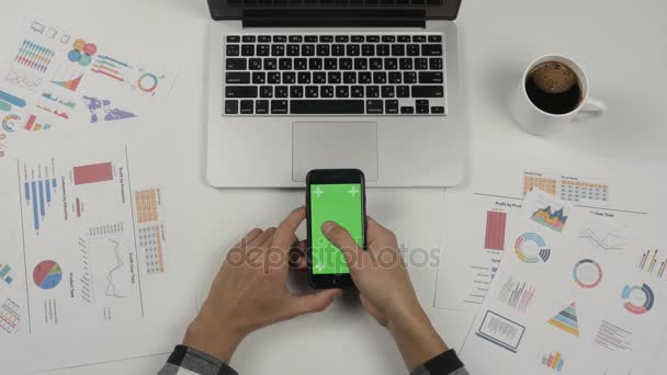 Businessman holding smartphone with green screen at white office table background. Male hands scrolling pages. — Stock Video