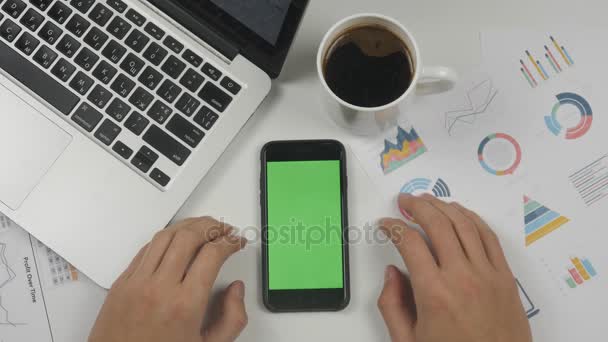 Empresario que usa smartphone con pantalla verde en el fondo de la mesa de la oficina blanca. Vista superior. Manos masculinas desplazándose páginas, zoom, tocando en la pantalla táctil. Escritorio de oficina fondo — Vídeos de Stock