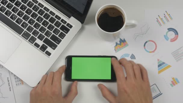 Man met smartphone aanraking met Chromakey, key groen scherm in horizontale positie op witte office tabelachtergrond. Kantoor spullen op Bureau achtergrond. — Stockvideo