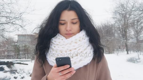 年轻的白种女人使用智能手机在冬季下雪时间. — 图库视频影像