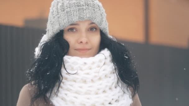 Portret van mooie jonge vrouw in hat op winter besneeuwde dag in de buitenlucht — Stockvideo