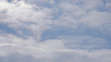 Güzel mavi gökyüzü, bulutlar sola taşır. Uçan bir uçağın penceresinden görünümü. Uçan bulutlarda
