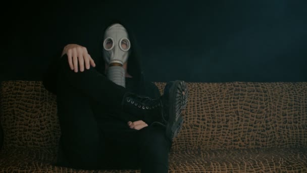 Człowiek w masce gazowej siedzi w dym w ciemnym pomieszczeniu. Stalker w post-apokaliptycznym świecie — Wideo stockowe