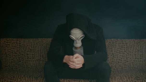 Man in een gas masker zit in rook in een donkere kamer. Stalker in de post-apocalyptische wereld — Stockvideo