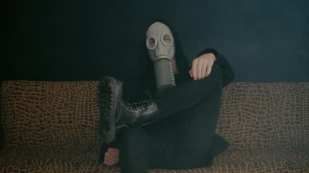 Man in een gas masker zit in rook in een donkere kamer. Stalker in de post-apocalyptische wereld — Stockvideo