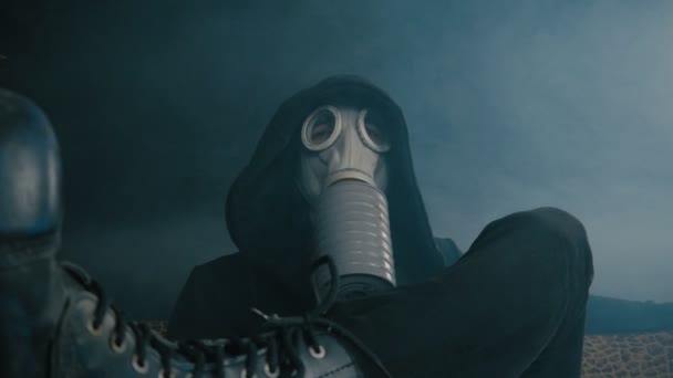 Uomo con una maschera antigas seduto in fumo in una stanza buia. Stalker nel mondo post-apocalittico — Video Stock