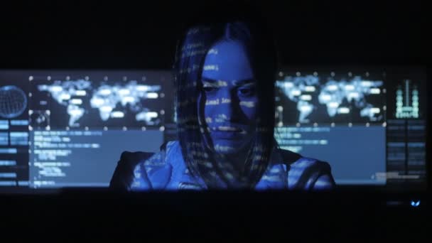 Žena Hacker programátor pracuje v centru zabezpečení cyber plné obrazovky v počítači. Binární kód na její tváři — Stock video