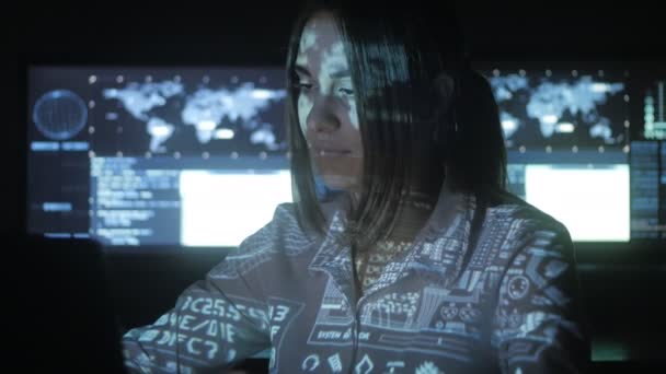 Femme programmeur Hacker travaille sur ordinateur dans le centre de cybersécurité rempli d'écrans d'affichage. Code binaire sur son visage 