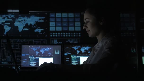Porträtt av ung kvinna programmerare arbetar på en dator i datacentret fylld med skärmar — Stockvideo