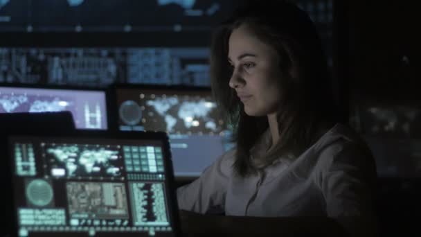 Портрет молодой женщины-программиста, работающей за компьютером в дата-центре, заполненном экранами — стоковое видео
