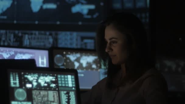 Retrato de una joven programadora que trabaja en una computadora en el centro de datos llena de pantallas — Vídeo de stock