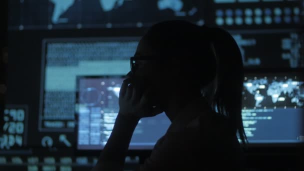 Silhouet van jonge vrouw het programmeur werkt op een computer in het datacenter gevuld met schermen — Stockvideo