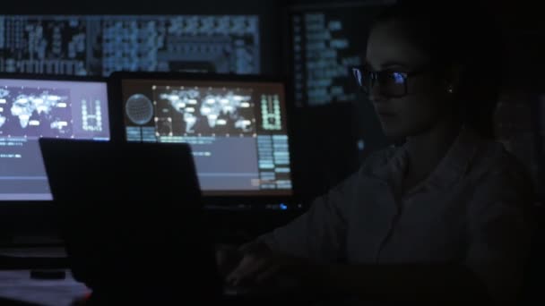 Portrait of young woman programmer working at a computer in the data center filled with display screens — Stock Video