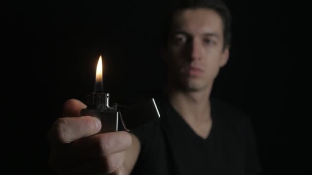 Apertura del hombre y la quema de hierro Zippo encendedor sobre un fondo negro — Vídeos de Stock