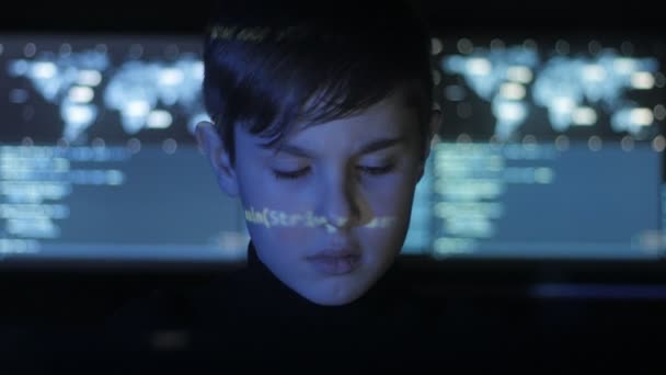 Adolescente bonito Boy hacker programador está trabalhando no computador no centro de segurança cibernética preenchido com telas de exibição. Código binário na cara dele — Vídeo de Stock