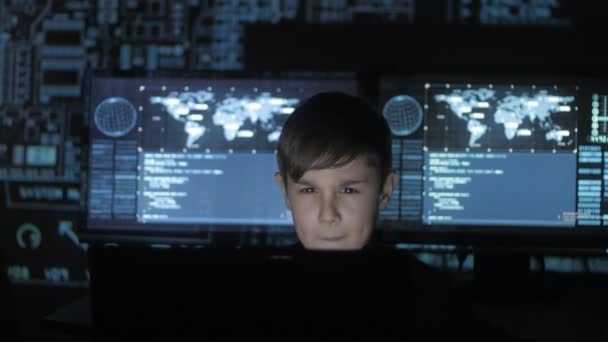 Young prodigy boy hacker programmer working at the computer in the data center filled with display screens. Portrait of Child prodigy hacker. — Stock Video