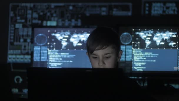 Söt teen pojke programmerare arbetar på en dator i datacentret fylld med skärmar. Porträtt av underbarn hacker. — Stockvideo