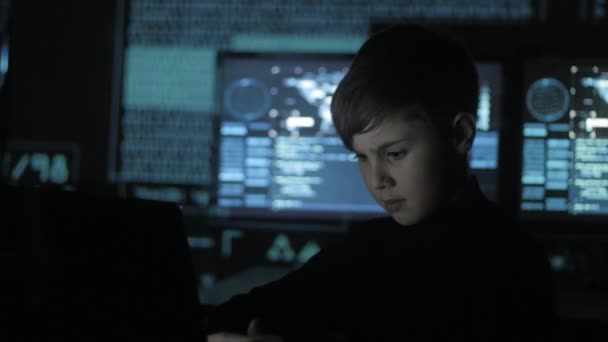 Programmeur adolescent mignon travaillant sur un ordinateur dans le centre de données rempli d'écrans d'affichage. Portrait d'enfant prodige hacker .