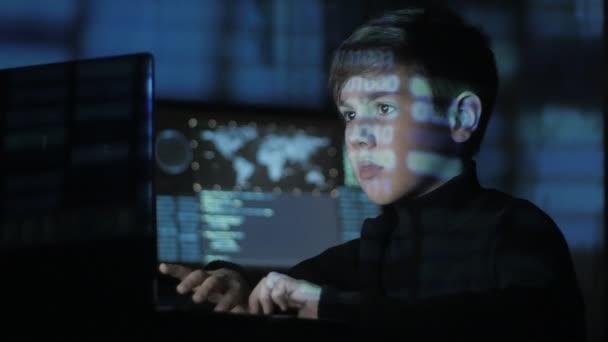 Carino teen Boy programmatore hacker sta lavorando sul computer nel centro di sicurezza informatica pieno di schermi di visualizzazione. Codice binario sul suo viso — Video Stock