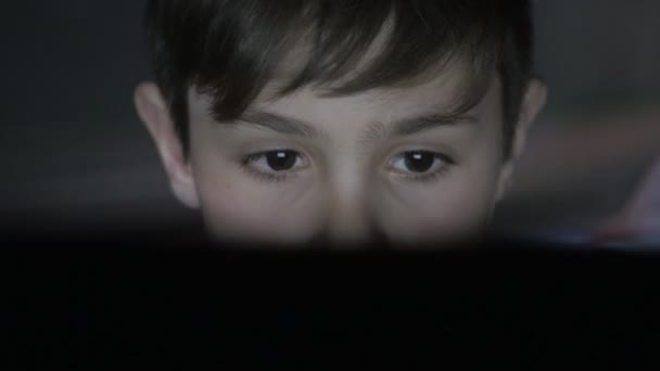 Gros plan de l'enfant jouant à un jeu vidéo sur la console. La projection du jeu sur le visage et sur le mur. Double exposition . — Video