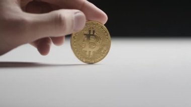 Bir madeni para bitcoin bir tablo üzerinde dönen bir adamın elini close-up. ağır çekimde. Kripto para birimi ve dijital para.
