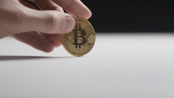 Gros plan d'une main d'un homme tournant une pièce Bitcoin sur une table. au ralenti. Monnaie cryptographique et argent numérique . — Video