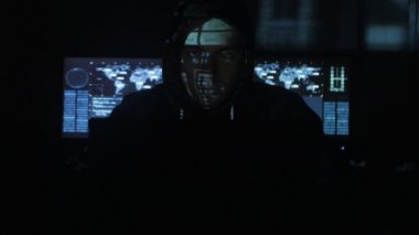 Adam hacker programcı ile dolu siber güvenlik Merkezi'ndeki yüzünde mavi kod karakterlerini yansıtan süre bilgisayar başında çalışma başlıklı görüntüleme ekranları.