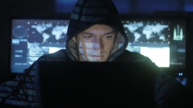 Adam geek hacker ile dolu siber güvenlik Merkezi'ndeki yüzünde mavi kod karakterlerini yansıtan süre bilgisayar başında çalışma başlıklı görüntüleme ekranları.