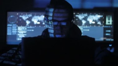 Hacker programcı bardaklarda yüzünü göstermek perde ile dolu siber güvenlik Merkezi'ndeki mavi kod karakterlerini yansıtan bilgisayarda çalışıyor.