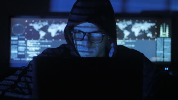 Mens geek hacker in kap met bril werkt op computer, terwijl blauw code tekens over zijn gezicht in cyber Beveiligingscentrum nadenken gevuld met schermen. — Stockvideo