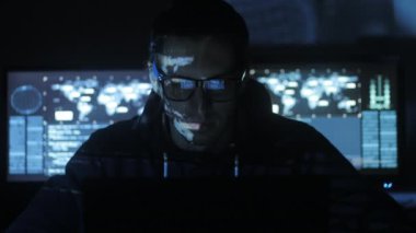 Siber Güvenlik Merkezi'ndeki yüzünde mavi kod karakterlerini yansıtan süre bilgisayar başında çalışan erkek hacker programcı göstermek perde ile dolu.
