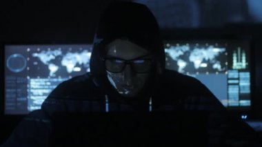 Adam geek hacker başlıklı gözlüklü siber güvenlik Merkezi'ndeki yüzünde mavi kod karakterlerini yansıtan süre bilgisayar başında çalışma göstermek perde ile dolu.