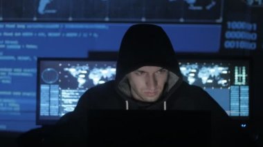 Adam geek hacker ile dolu siber güvenlik Merkezi'ndeki yüzünde mavi kod karakterlerini yansıtan süre bilgisayar başında çalışma başlıklı görüntüleme ekranları.