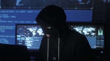 Maskeli tehlikeli hacker sistemi güvenlik şifresini bulmak için kodları ve numaraları kullanarak girmek için çalışır. Siber Suçlar kavramı.