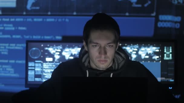 Geek Hacker programmeur travaille sur ordinateur dans le centre de cybersécurité rempli d'écrans d'affichage .