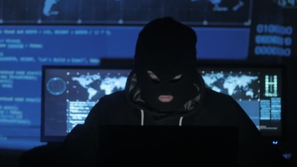 Анонімний хакер у масці намагається ввести систему за допомогою кодів і цифр, щоб дізнатися пароль безпеки. Концепція кіберзлочинності . — стокове відео