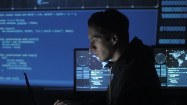 Geek Hacker programmeur travaille sur ordinateur dans le centre de cybersécurité rempli d'écrans d'affichage . — Video