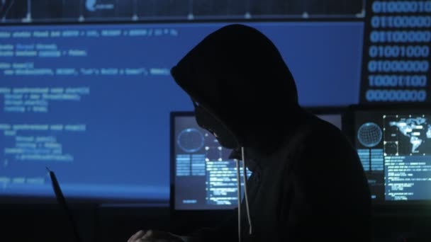 Anonyme Hacker in der Maske versuchen, mit Codes und Nummern in das System einzudringen, um das Sicherheitspasswort herauszufinden. das Konzept der Cyberkriminalität. — Stockvideo