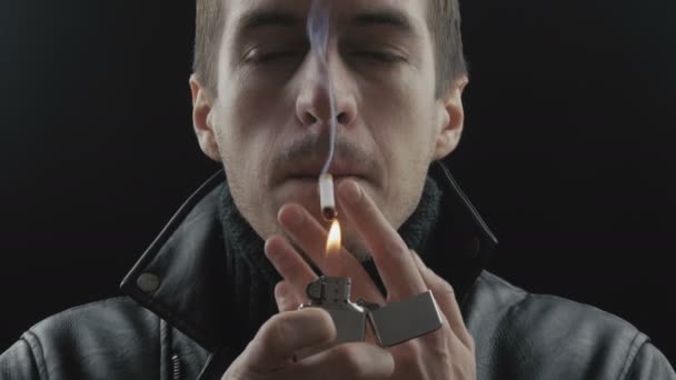 Крупный план молодого человека курит сигареты на черном фоне — стоковое видео