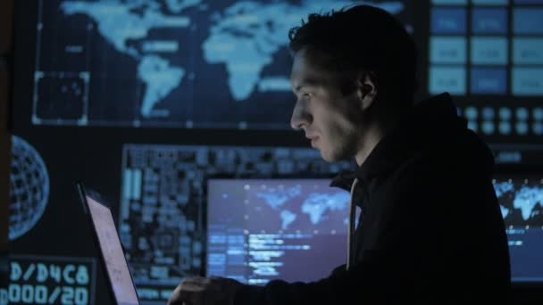 Retrato de un joven programador trabajando en una computadora en el centro de datos lleno de pantallas de visualización — Vídeos de Stock