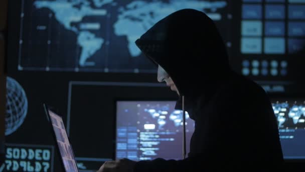 Hombre geek hacker en la capucha de trabajo en la computadora en el centro de seguridad cibernética lleno de pantallas . — Vídeo de stock