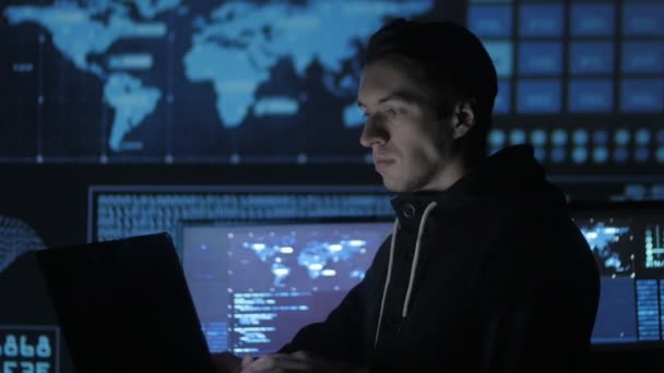 Portret van een jonge programmeur werkt op een computer in het datacenter gevuld met schermen — Stockvideo