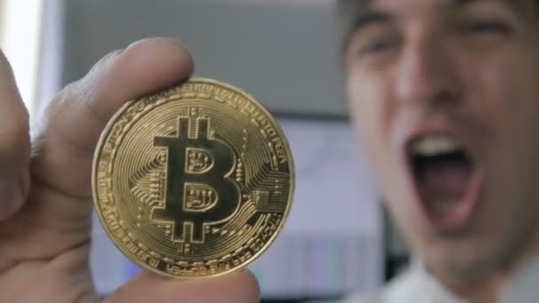 Κοντινό πλάνο της κατέχει κατάπληκτος έκπληκτος νέος επιχειρηματίας Btc Bitcoin στο χέρι. Επιτυχία σε κέρδη στην αγορά κρυπτο-νόμισμα — Αρχείο Βίντεο