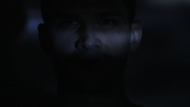 ビデオまたはテレビまたはコンピューター モニターのフィルムを見ている若い男の目を閉じます。彼の顔に反射 — ストック動画