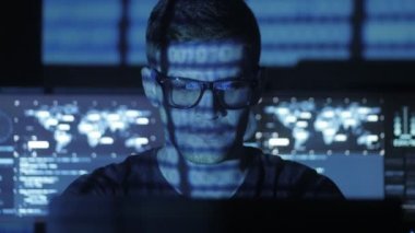 Hacker programcı bardaklarda yüzünü göstermek perde ile dolu siber güvenlik Merkezi'ndeki ikili kod karakterlerini yansıtan mavi bilgisayar üzerinde çalışıyor.