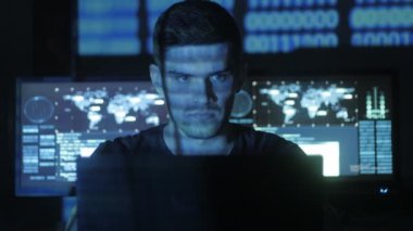 Siber Güvenlik Merkezi'ndeki yüzünde mavi kod karakterlerini yansıtan süre bilgisayar başında çalışan erkek hacker programcı göstermek perde ile dolu.