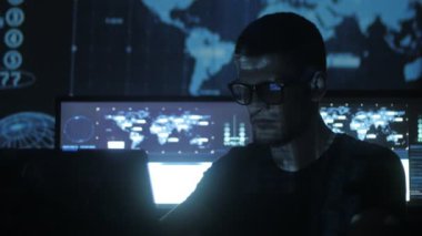 Hacker programcı bardaklarda yüzünü göstermek perde ile dolu siber güvenlik Merkezi'ndeki ikili kod karakterlerini yansıtan mavi bilgisayar üzerinde çalışıyor.